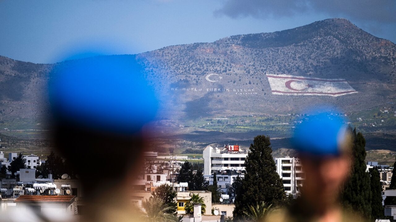UN peacekeepers in the buffer zone in the divided capital of Nicosia. In the distance, the flag of the self-proclaimed Turkish Republic of Northern Cyprus is seen on the island's northern Kyrenia mountain range