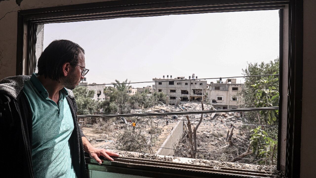 Mohammed Sarsour looks out from one of the windows of his damaged apartment in Deir al-Balah in the central Gaza Strip, days after it was hit by an Israeli air strike