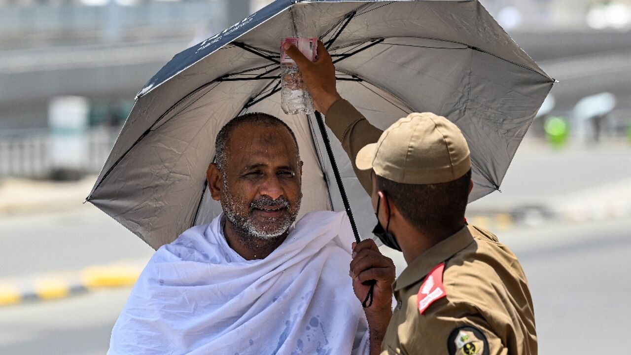 A security official sprays water on a Muslim pilgrim as he arrives in Mina, near Mecca