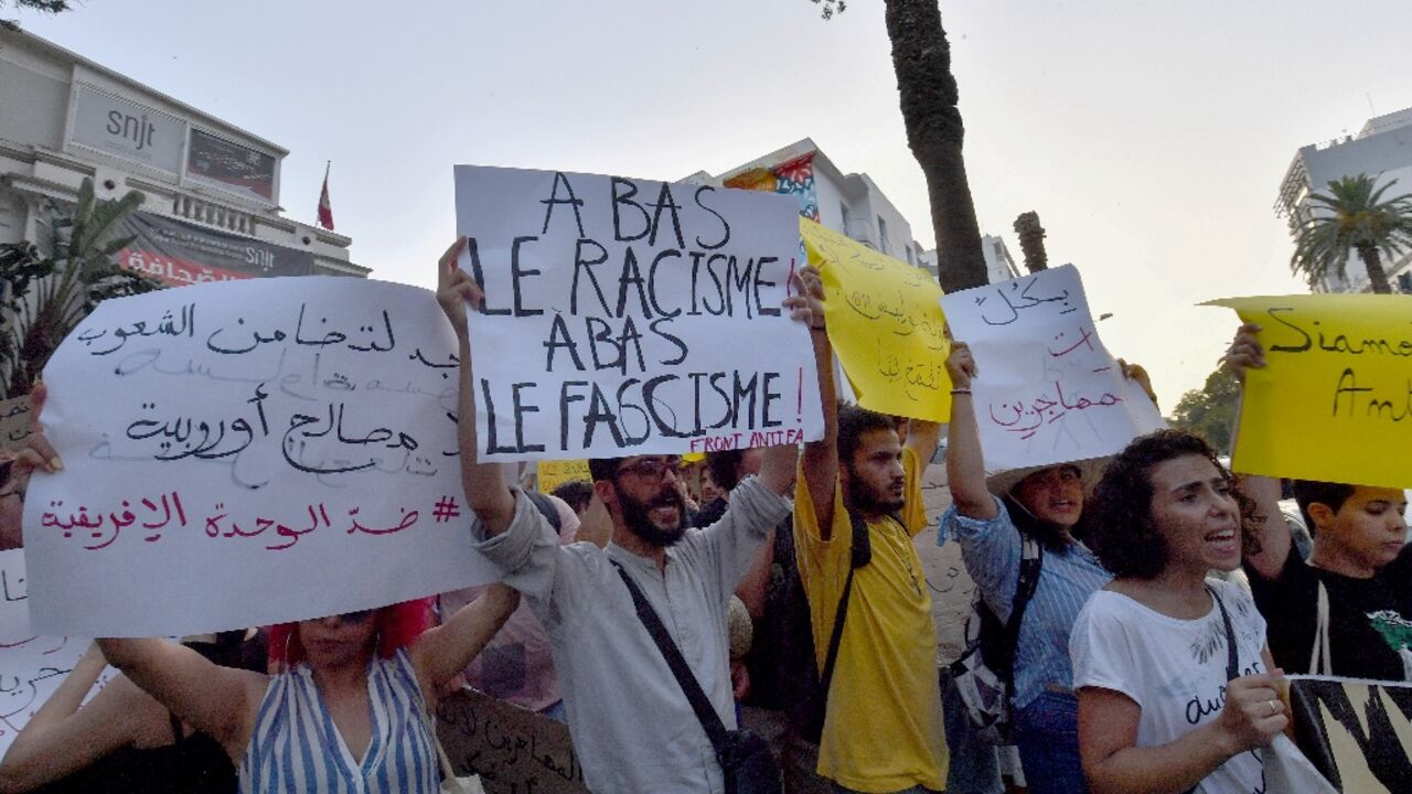 Demonstrators lift placards and chant anti-racism slogans during a protest in Tunis in support of migrants