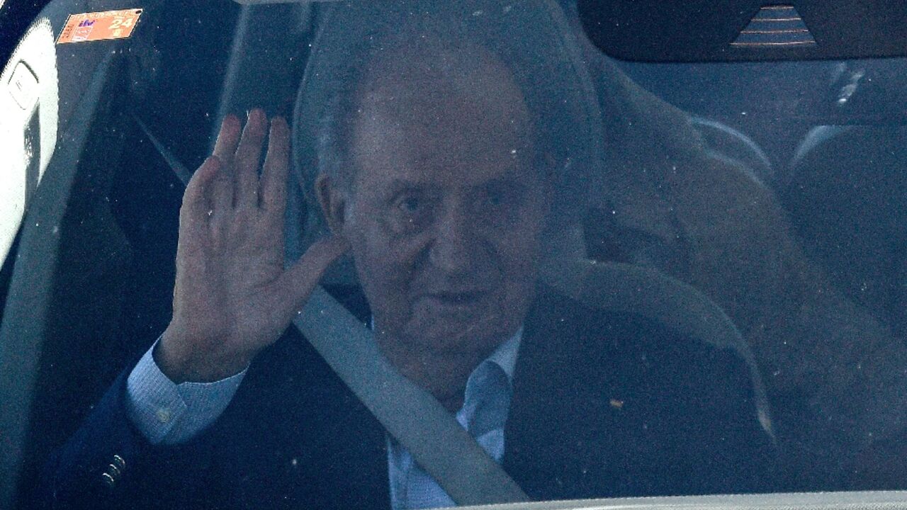 Spain's former King Juan Carlos waves in a car upon his arrival in Vigo airport