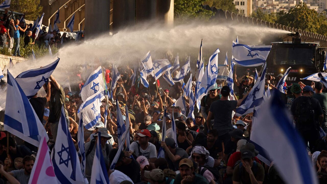 Israeli security forces use a water cannon to disperse demonstrators blocking the entrance of the Knesset.