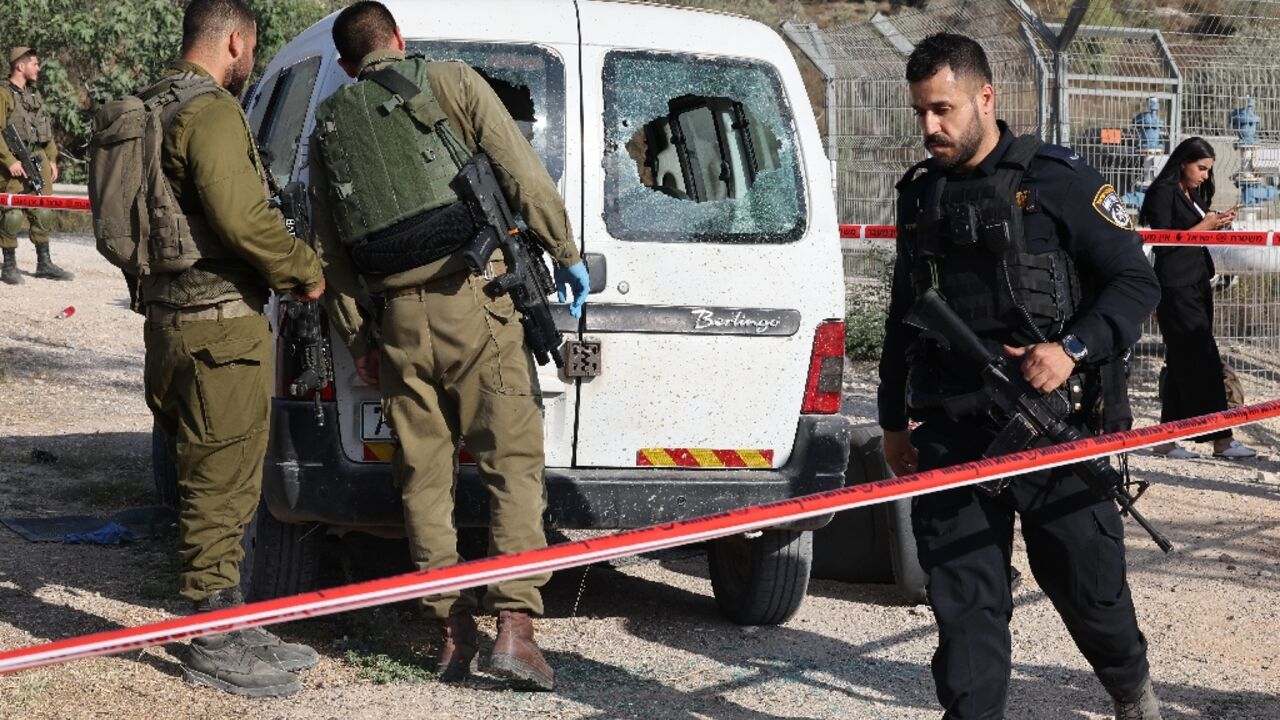 Israeli soldiers examine a damaged car following a reported attack in the occupied West Bank