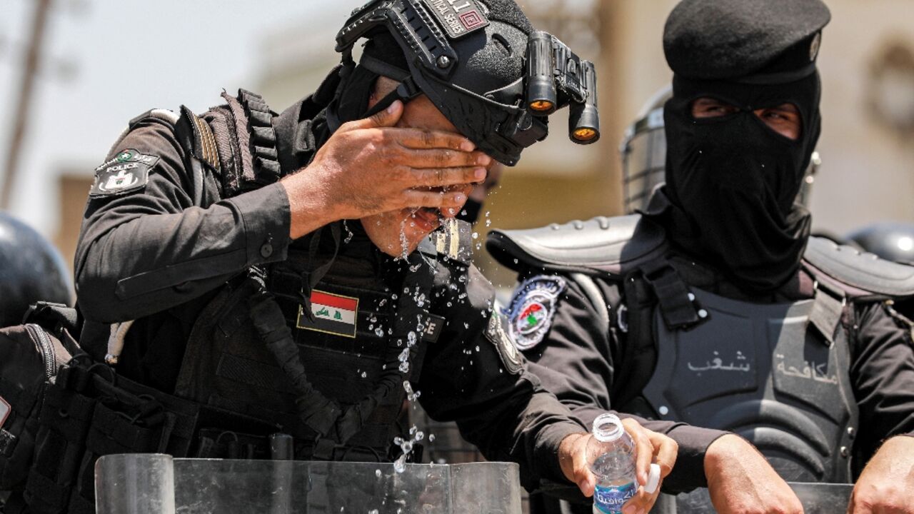 An Iraqi security forces member, on duty at the demonstration against power and water shortages, tries to cool off in Baghdad