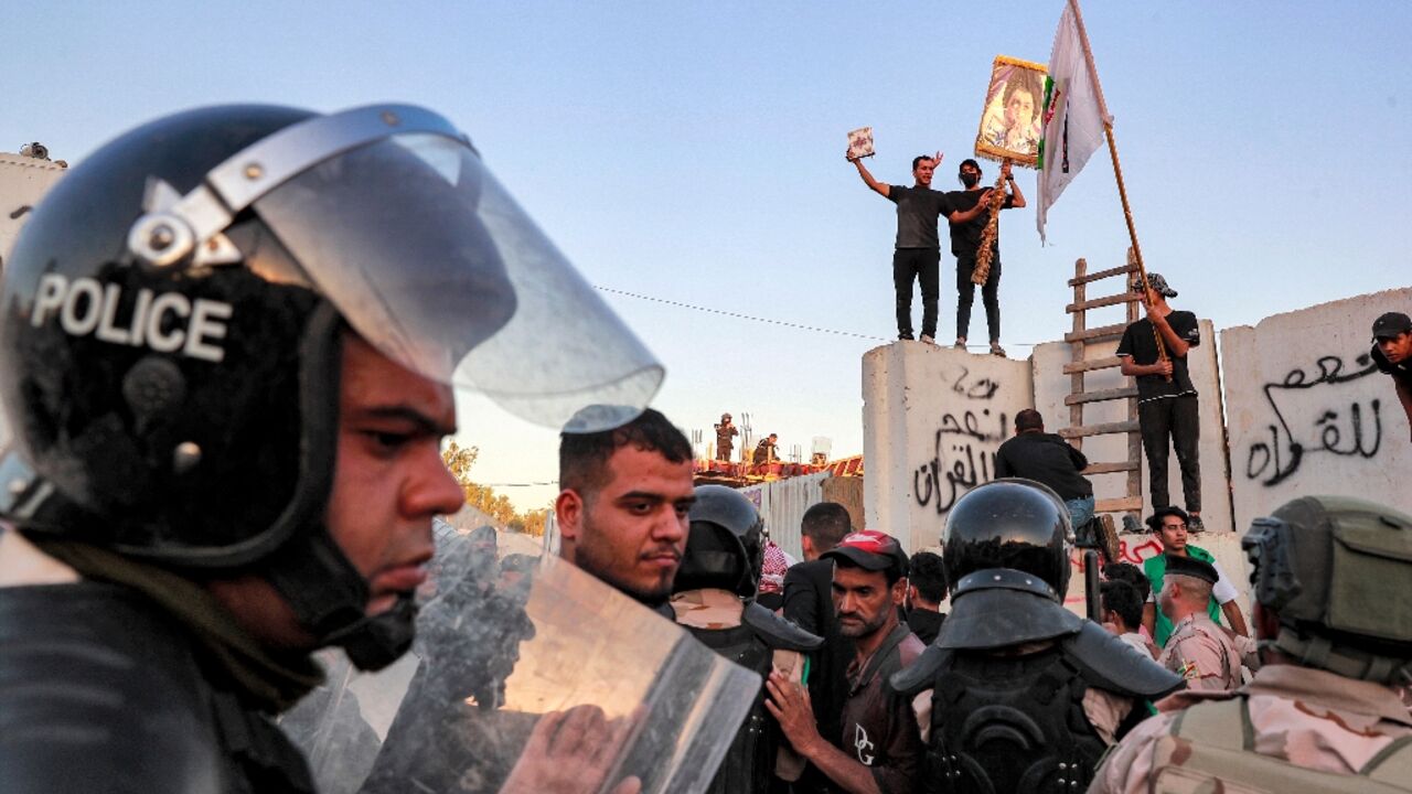 Iraqi riot police try to disperse protesters who breached the Swedish embassy compound and set fires inside