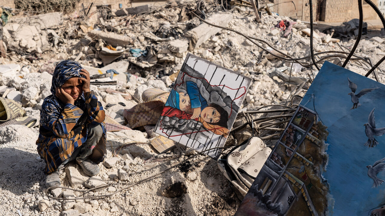 A child watches as Jasmine (not pictured) paints amidst the rubble in the city of Jindires on Feb. 28, 2023, near Aleppo, Syria.