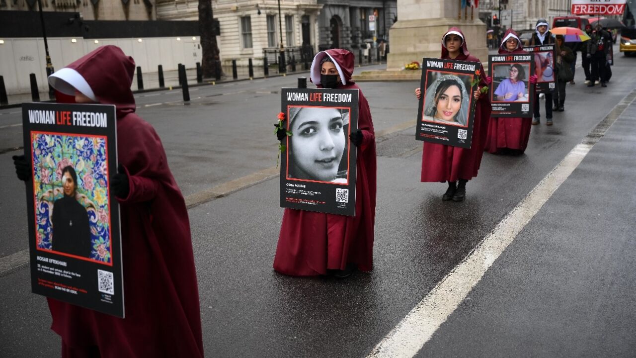 Demonstrators hold placards reading "Women, Life, Freedom" in support of Iranian women at a rally in central London on March 8, 2023