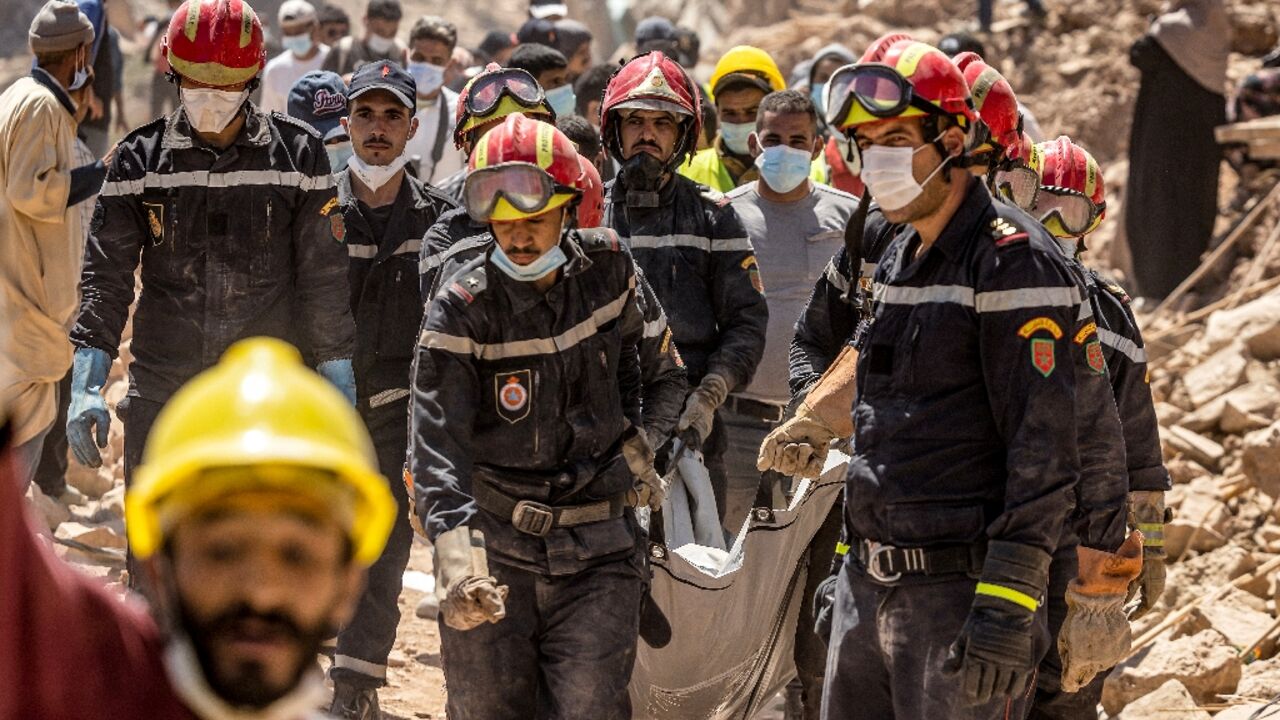Rescue workers carry a body recovered from the rubble of an earthquake-damaged house in Morocco 