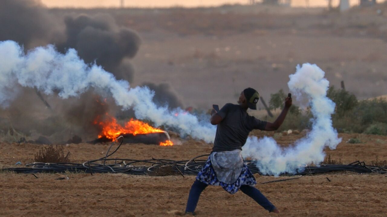 A Palestinian demonstrator throws back a tear gas canister fired by Israeli troops during clashes along the Gaza border