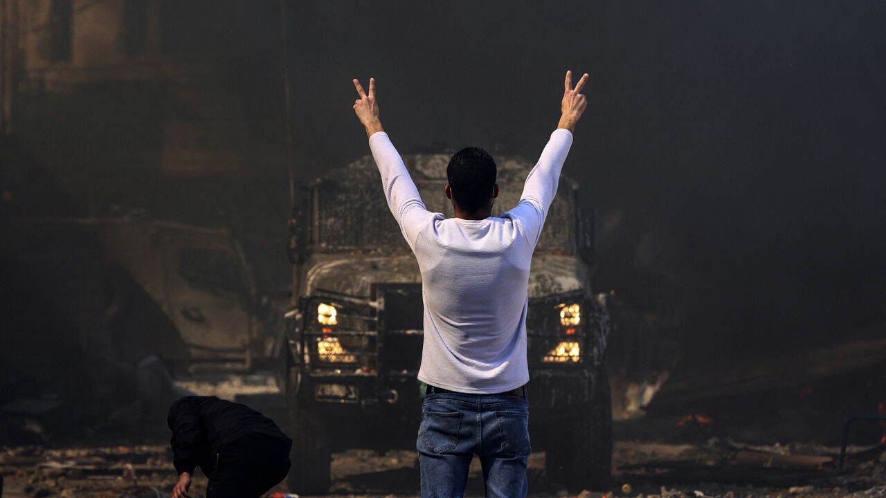 A Palestinian man flashes the victory sign as he faces an Israeli military vehicle, during a raid on the occupied-West Bank city of Nablus, February 22, 2023.