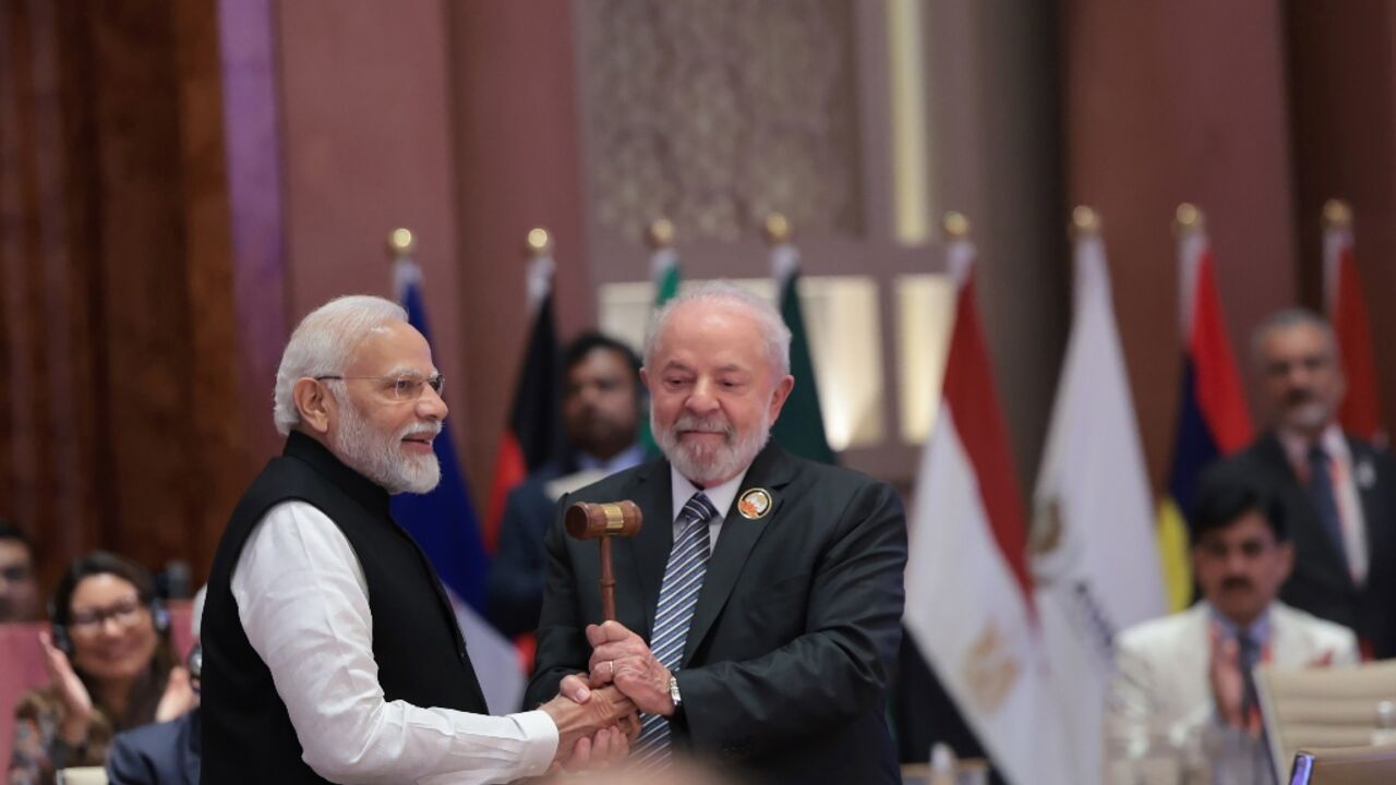 India's Prime Minister Narendra Modi (L) hands over the gavel to Brazil's President Luiz Inacio Lula da Silva (R) and the end of the G20 summit