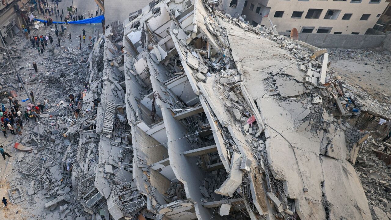 People inspect the ruins of a building destroyed in Israeli strikes in Gaza City on October 8, 2023