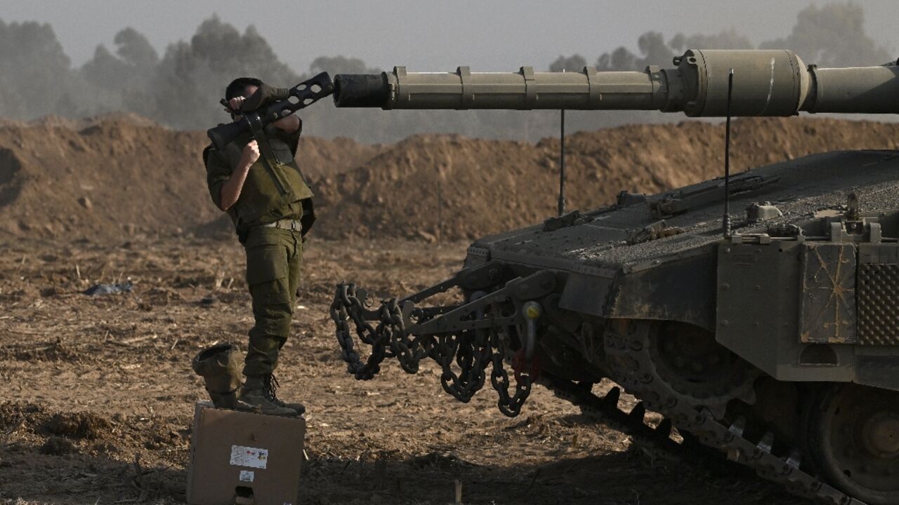 An Israeli solider checks the gun of a Merkava tank deployed along Israel's border with Gaza