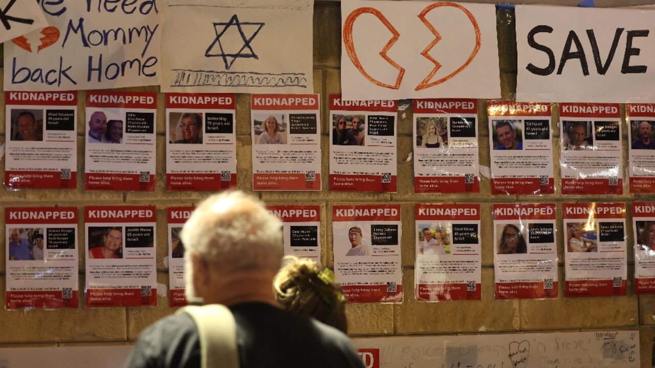 People gather next to a wall in Tel Aviv bearing the portraits of those kidnapped during the October 7 attack on Israel's south