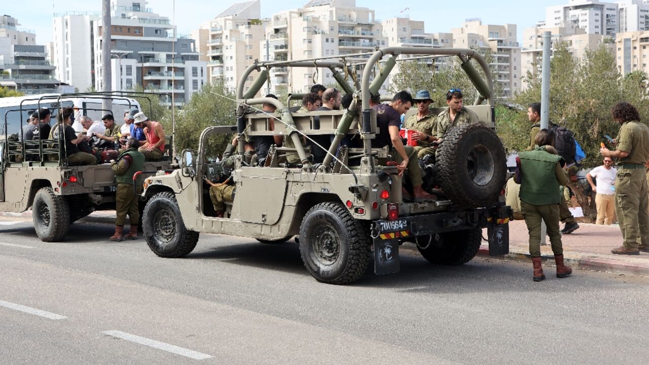Israeli army reservists are transported in military vehicles to join their army base, south of Tel Aviv on October 7, 2023 