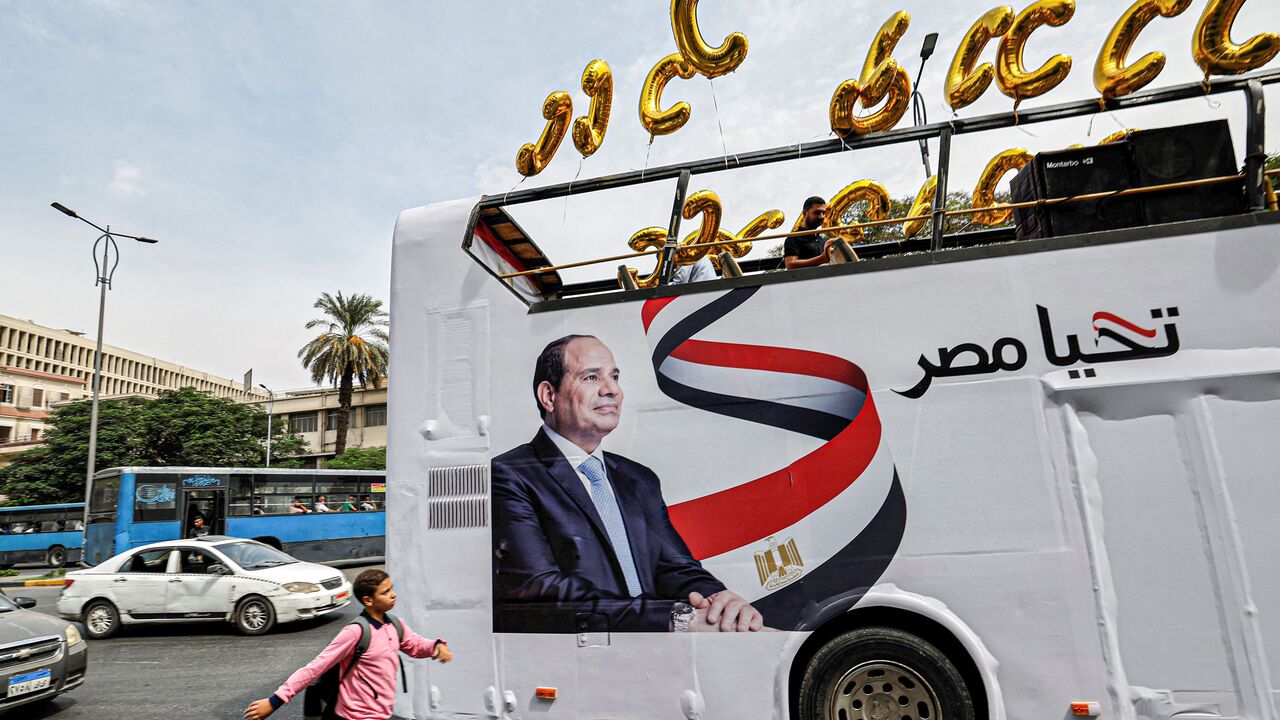 A school boy walks near an election campaign bus for Egypt's President Abdel Fattah al-Sisi adorned with his image, his slogan "long live Egypt", and C-shaped balloons, as Sisi's supporters prepare for a rally in Giza, the twin-city of the Egyptian capital, on October 2, 2023. (Photo by Khaled DESOUKI / AFP) (Photo by KHALED DESOUKI/AFP via Getty Images)