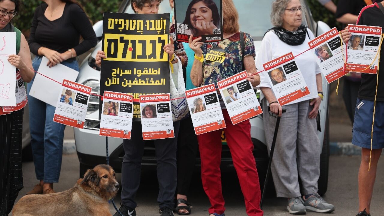 Demonstrators carry posters with the images of hostages held in Gaza outside the Israeli president's residence in Jerusalem