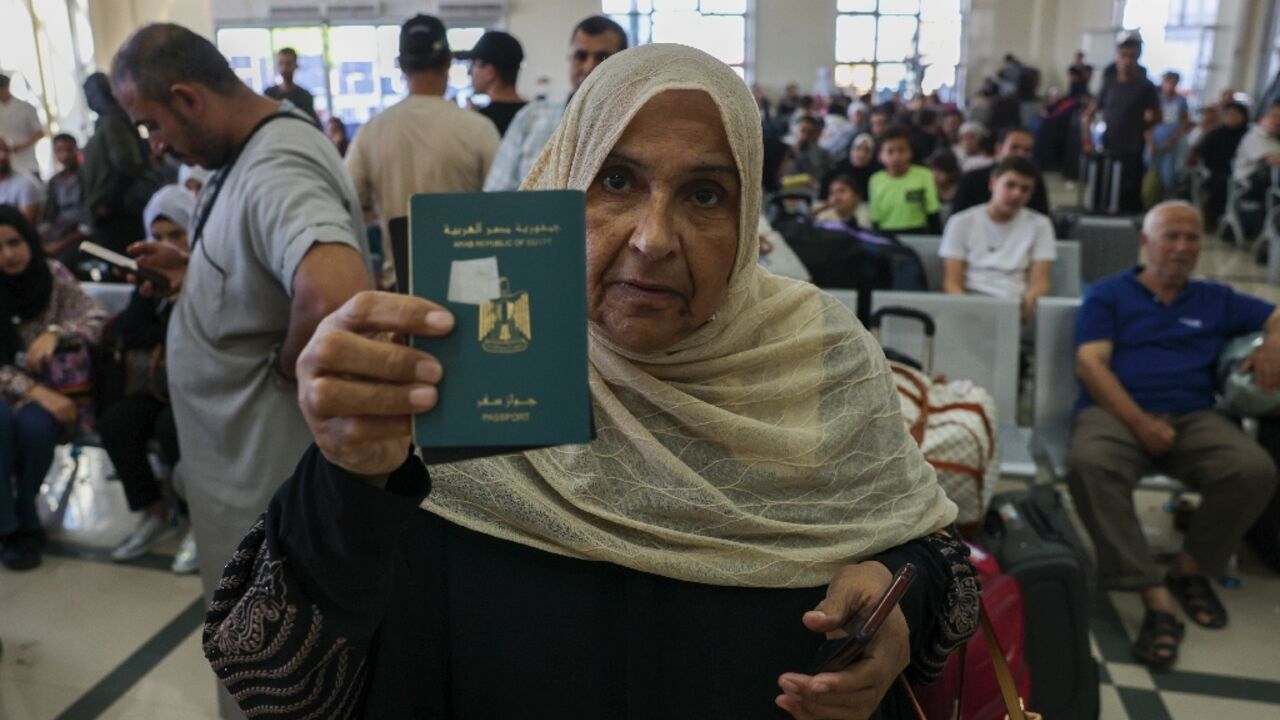 A woman shows her passport as Palestinian dual nationals and foreigners wait to cross the Rafah border crossing with Egypt, in the southern Gaza Strip, on November 7, 2023,