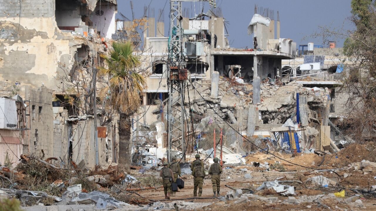 Israeli troops walk past destroyed buildings along the north-south Salaheddine road in Gaza
