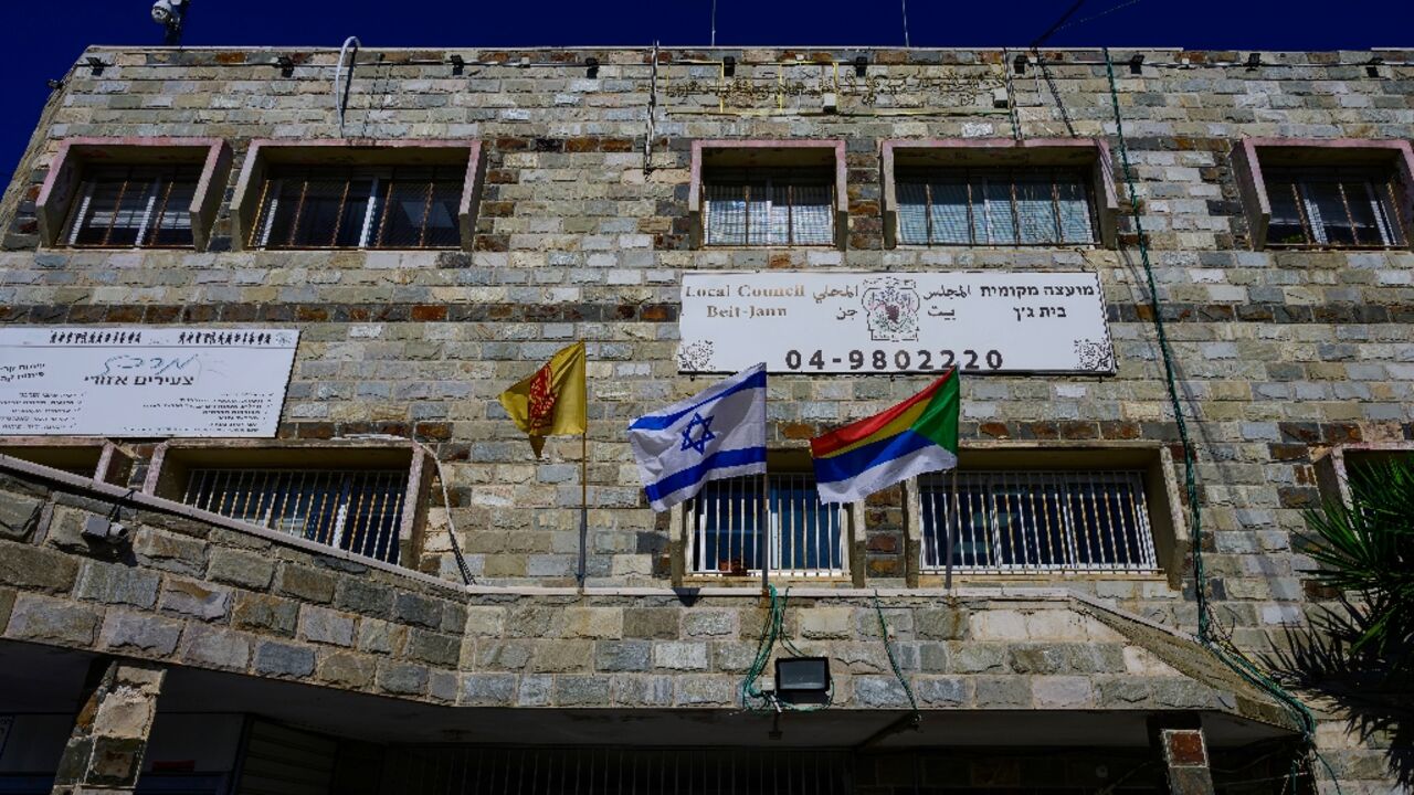 Druze (R) and Israeli (C) flags fly outside the local council building in the predominantly Druze city of Beit Jann in northern Israel