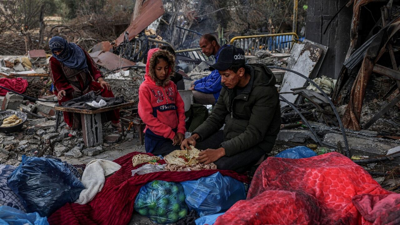 Palestinians eat outside amid the destruction caused by Israeli strikes in the Gaza Strip