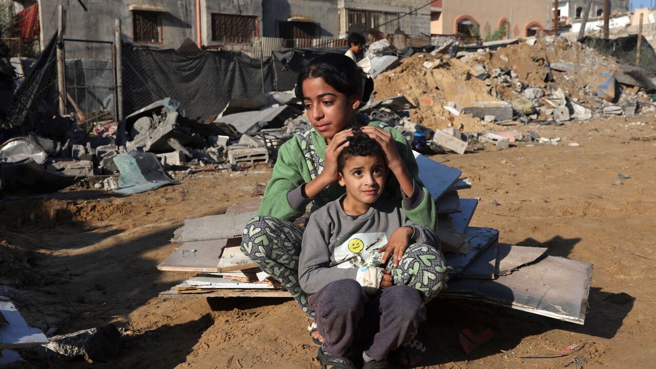 TOPSHOT - A Palestinian girl and her brother sit amidst the debris of a house following an Israeli strike in Rafah in the southern Gaza Strip on November 18, 2023, amid ongoing battles between Israel and the Palestinian group Hamas. (Photo by MOHAMMED ABED / AFP) (Photo by MOHAMMED ABED/AFP via Getty Images)
