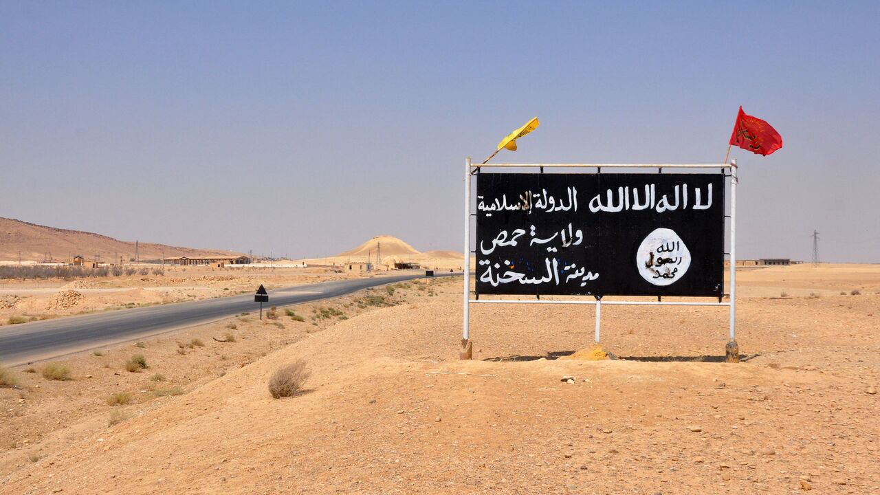 A general view taken on Aug. 13, 2017 shows an Islamic State (IS) group poster in the central Syrian town of Al-Sukhnah as pro-government fighters clear the area after taking control of the city situated in the county's large desert area called the Badiya. 