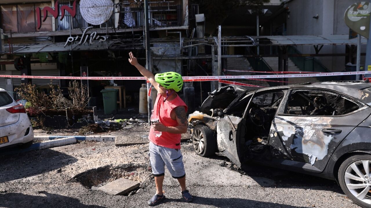 A man  gestures towards the damage from the rocket attack on Kiryat Shmona