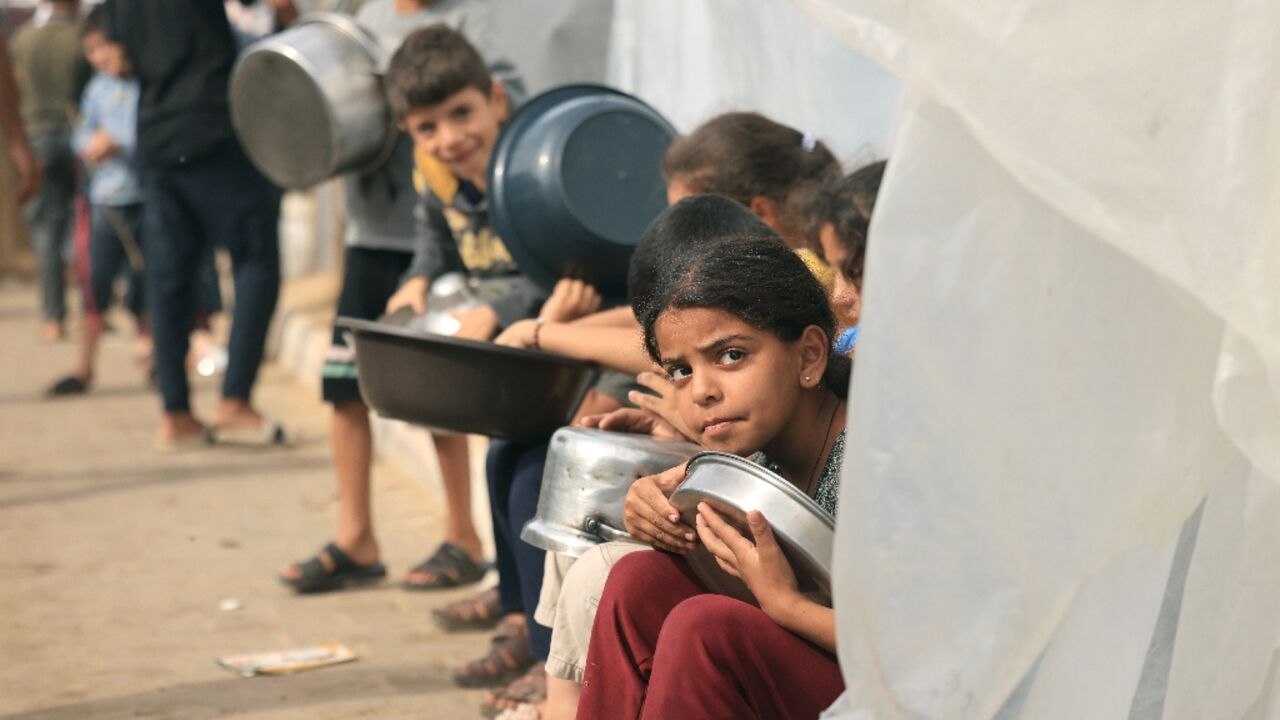 Displaced Palestinian children wait for food in Khan Yunis