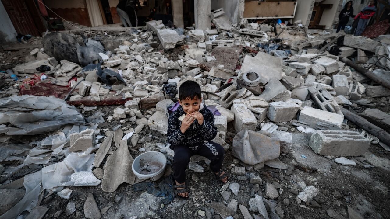 A child eats amid the rubble of destroyed buildings following Israeli bombardment in Rafah in the southern Gaza Strip