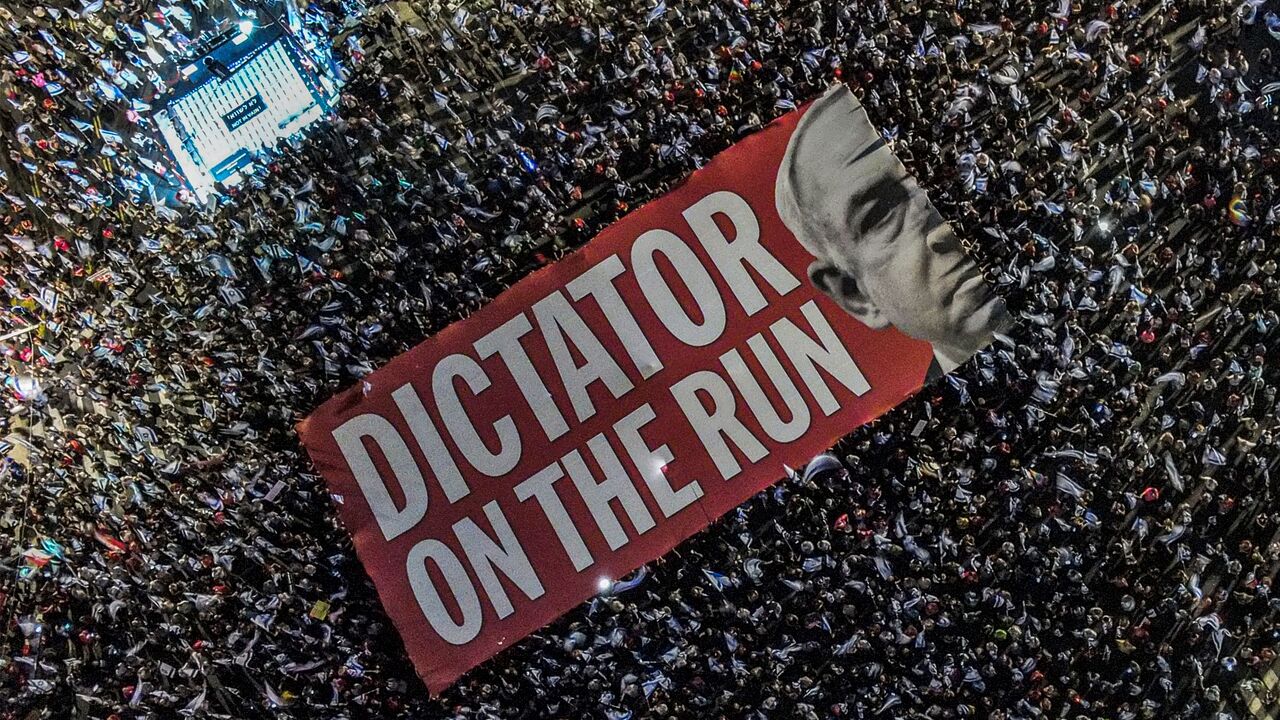 TOPSHOT - This aerial view shows demonstrators unfurling a giant banner against Israeli Prime Minister Benjamin Netanyahu during a rally against the Israeli government's judicial overhaul plan near Azrieli Mall in Tel Aviv on September 23, 2023. (Photo by Jack GUEZ / AFP) (Photo by JACK GUEZ/AFP via Getty Images)