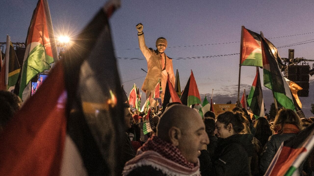 Palestinians gather around a statue of late South African president Nelson Mandela in Ramallah to celebrate a landmark "genocide" case filed by South Africa against Israel at the International Court of Justice