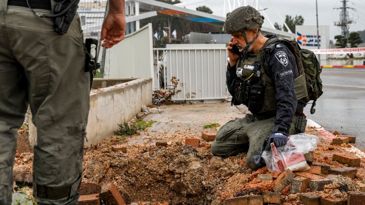 An Israeli policeman inspects the impact crater left by a rocket fired from southern Lebanon in the northern city of Safed