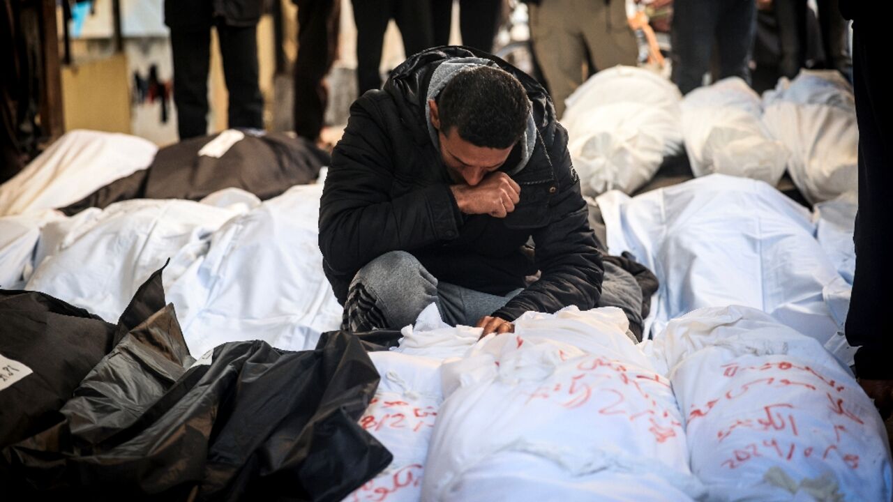 A Palestinian man mourns over shrouded bodies of relatives killed in overnight Israeli bombardment on the southern Gaza Strip at Al-Najjar hospital in Rafah on February 8, 2024