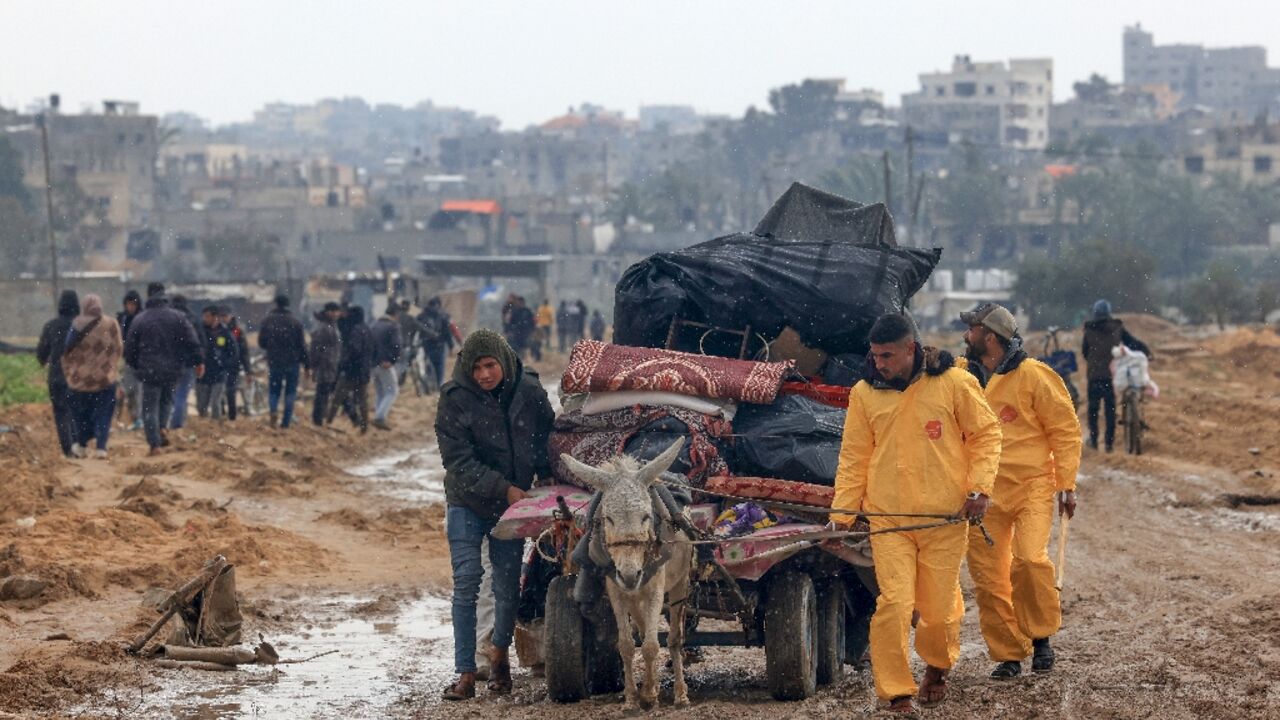 Some civilians fleeing the southern Gaza city of Khan Yunis wear hazmat suits left over from the Covid pandemic to keep warm as winter storms lash the Palestinian territory