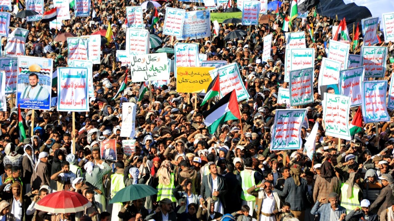 Yemenis lift placards and wave Palestinian flags as they march in the Huthi-run capital Sanaa on February 23, 2024