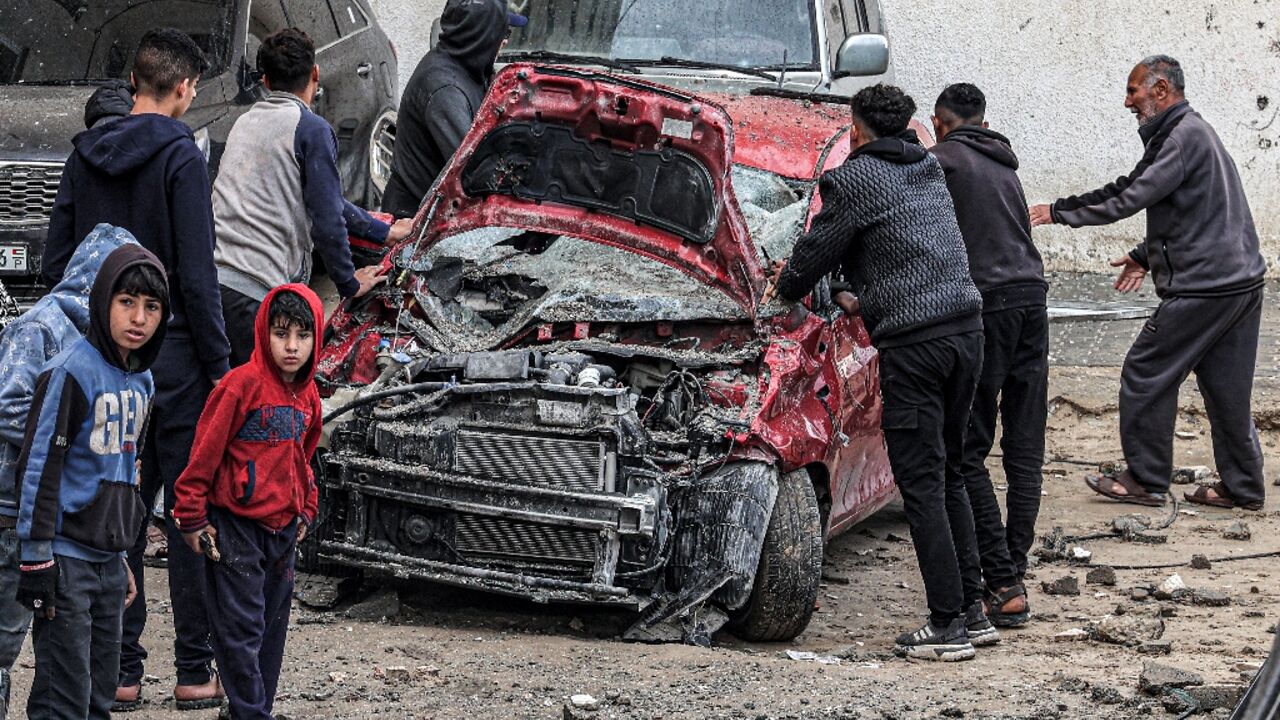 Men and boys gather to inspect a destroyed vehicle following overnight Israeli bombardment at the Rafah camp in southern Gaza