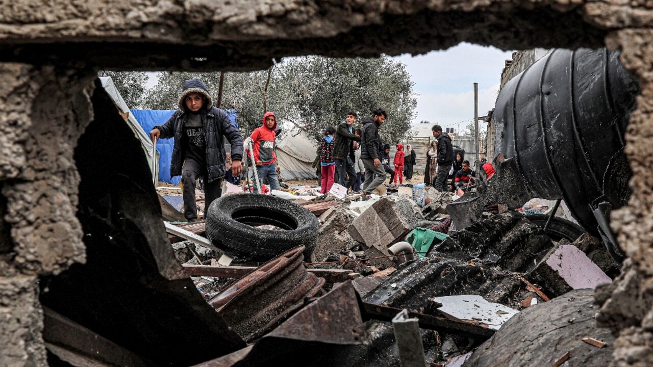Displaced Palestinians inspect the damage to their tents following overnight Israeli bombardment in Rafah 