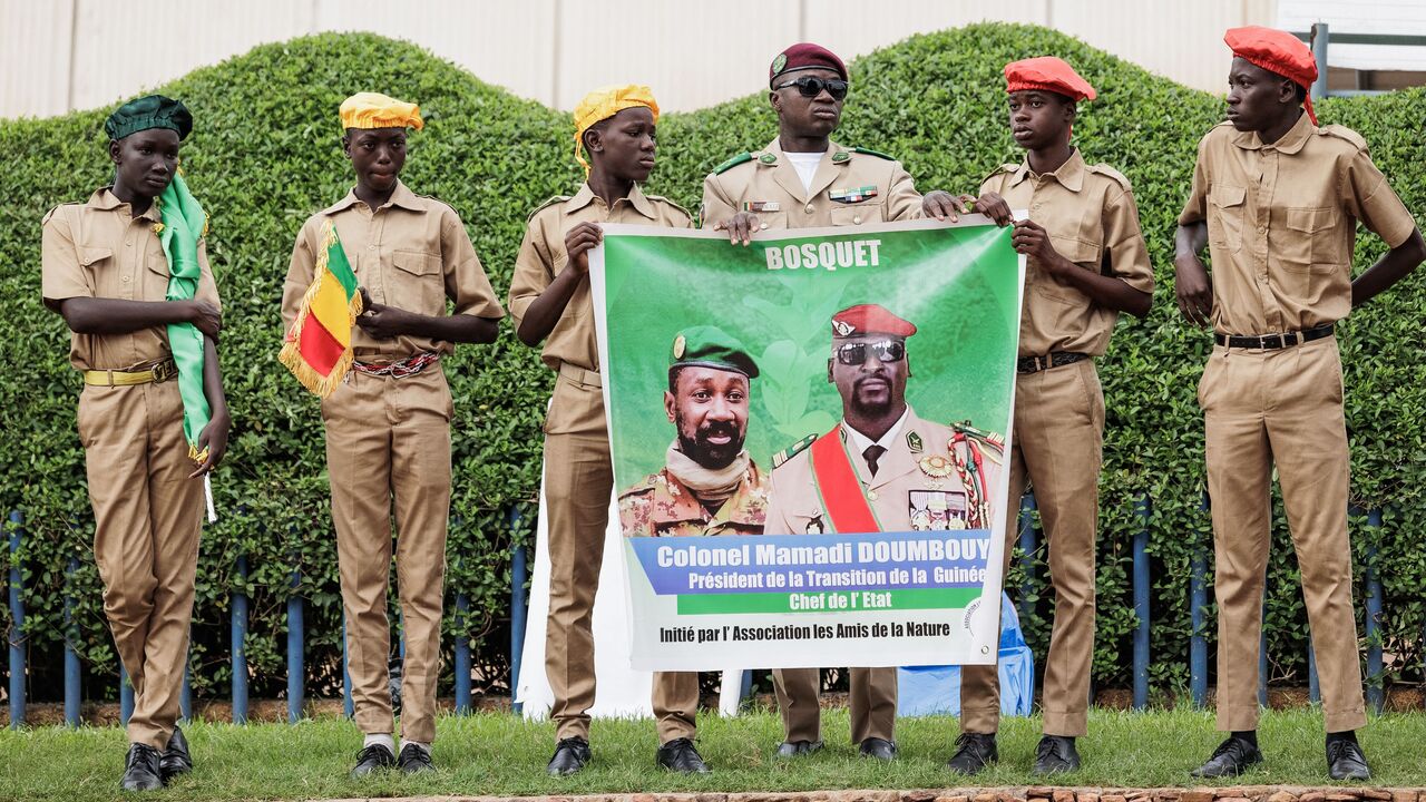 Supporters hold a poster depicting Malis interim leader and head of Junta, Colonel Assimi Goïta (L) and Guinea Interim leader and head of Junta, Mamady Doumbouya (R), in Bamako, Mali, on September 22, 2022 during Mali's Independence Day military parade. (Photo by OUSMANE MAKAVELI / AFP) (Photo by OUSMANE MAKAVELI/AFP via Getty Images)