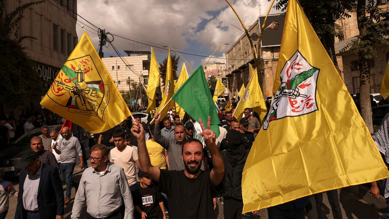 A man raises the Hamas flag as other wave the Fatah emblem during a demonstration in the occupied West Bank city of Hebron to show solidary with the Palestinians of the Gaza Strip on Oct. 20, 2023.