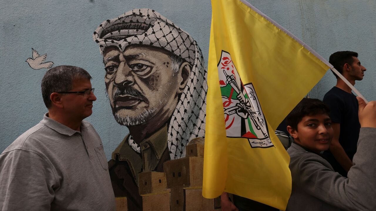 A young boy carries the flag of Fatah as he walks past a mural painting of late Palestinian leader Yasser Arafat, during a solidarity march with the Palestinians of the Gaza Strip on Oct. 27, 2023.