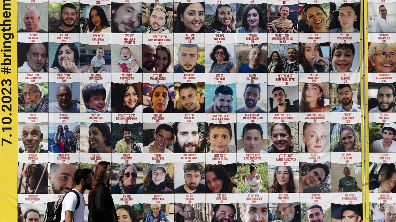 People pass by a building covered with photos of hostages who have been released or are still being held in the Gaza Strip, on March 26, 2024 in Tel Aviv, Israel.