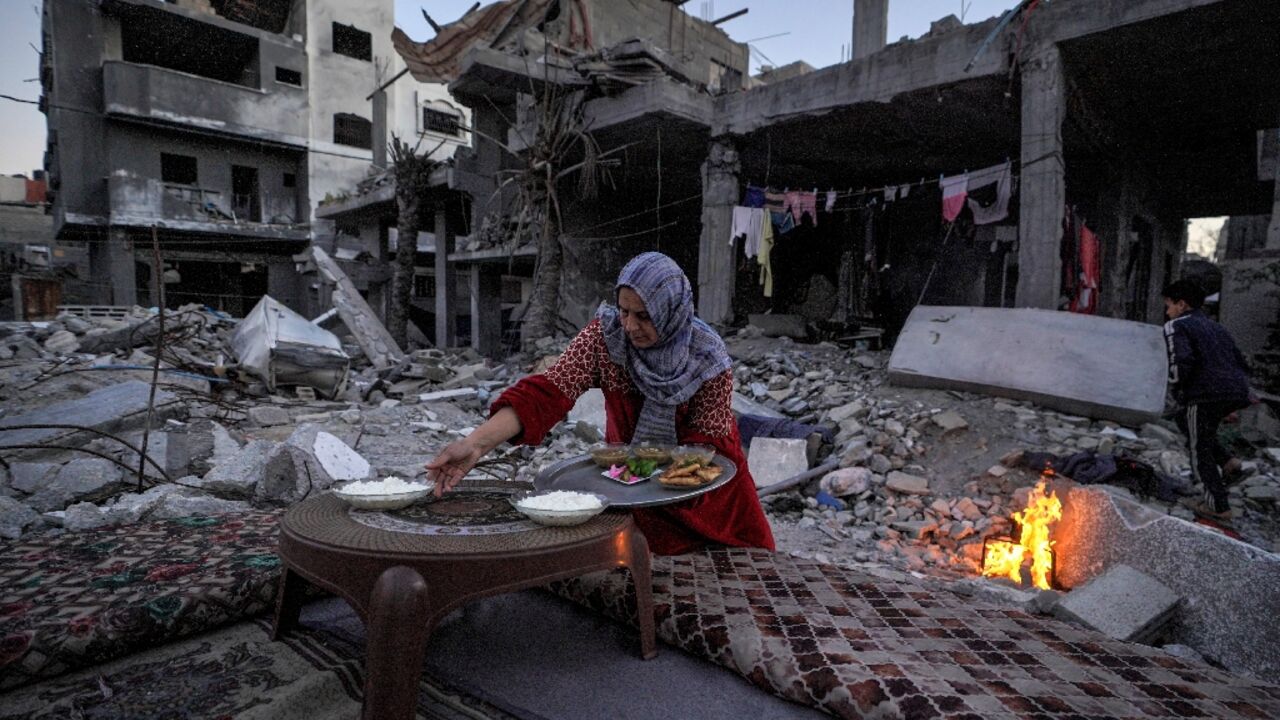 A Palestinian woman prepares a traditional Ramadan iftar meal amid the ruins of her family's house
