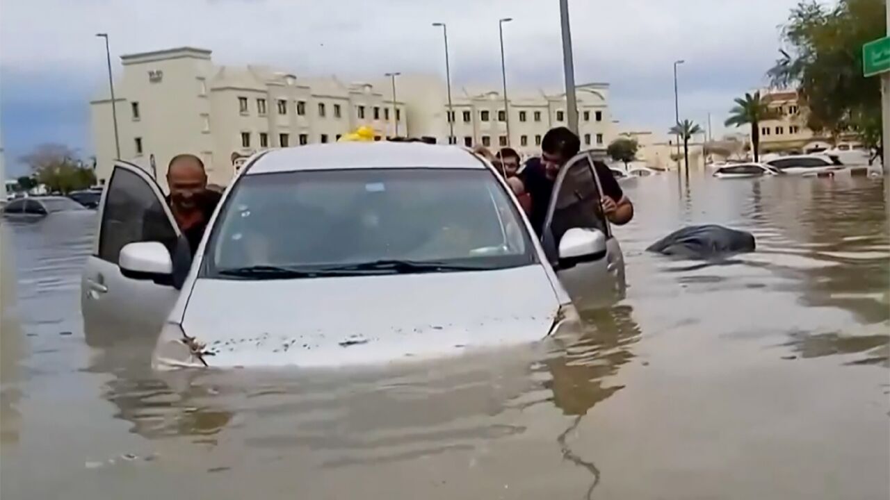 Residents push a waterlogged car along a flooded street in the desert city of Dubai after torrential rains paralysed the Gulf financial and leisure hub