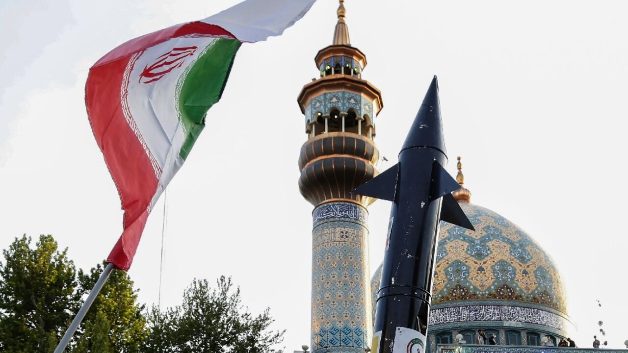 Iranians lift up a flag and the mock up of a missile during a celebration following Iran's missiles and drones attack on Israel, on April 15 2024, at Palestine square in central Tehran