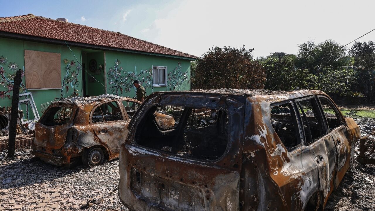 An Israeli soldier walks past charred cars in the small farming community of Netiv Haasara where Maoz Inon's parents were killed by Palestinian militants on October 7