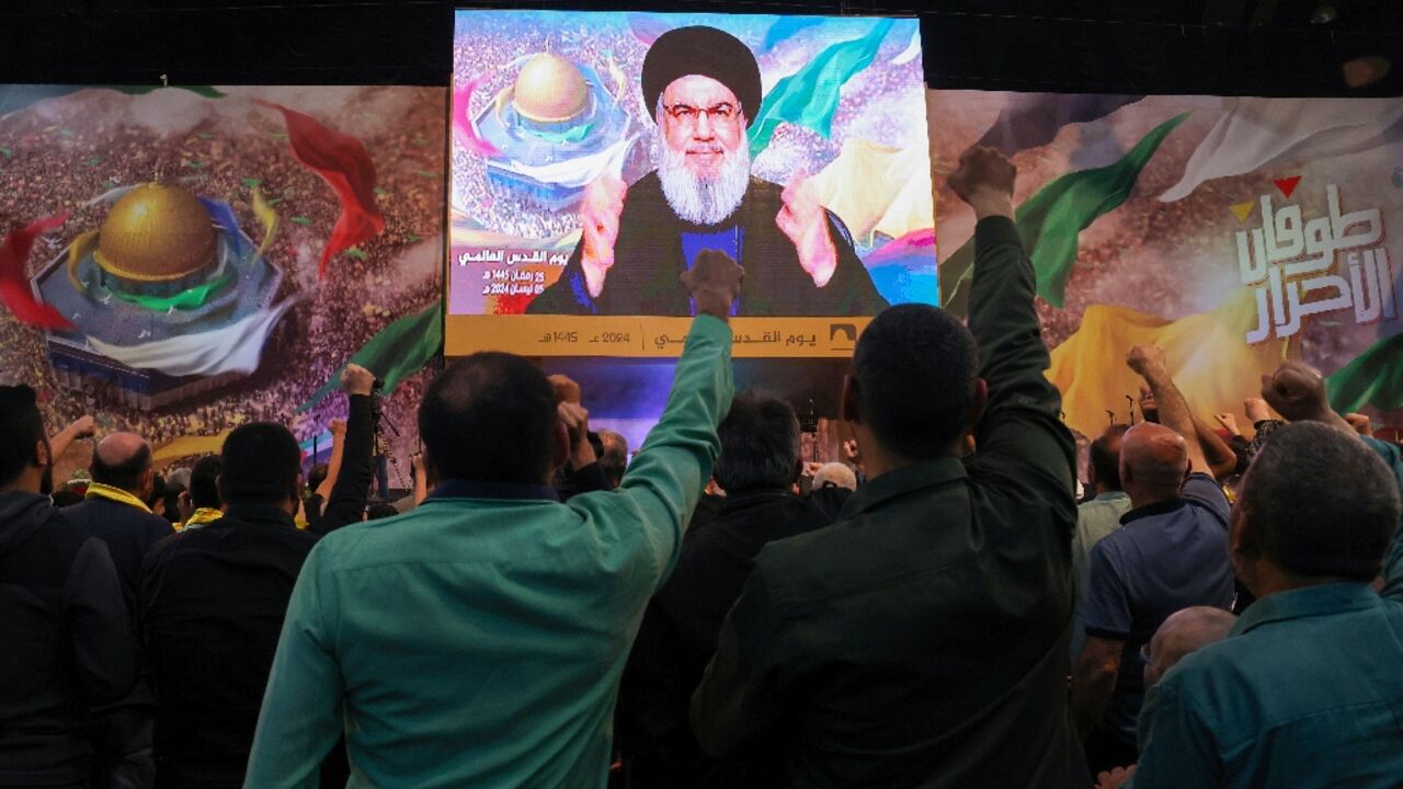 Hezbollah supporters watch their leader Hassan Nasrallah's speech on a big screen at a Quds (Jerusalem) Day gathering in Beirut's southern suburbs