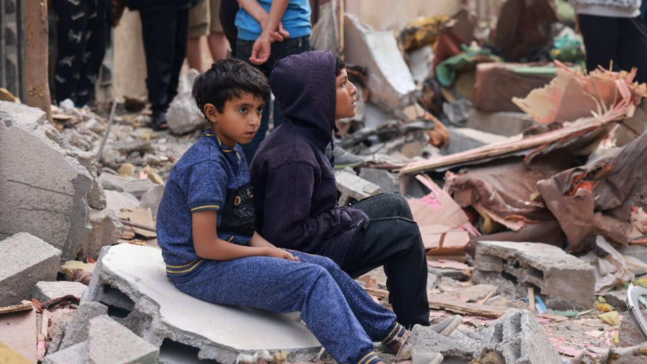 Palestinian boys sit on building rubble following overnight Israeli bombardment in Rafah in the southern Gaza Strip