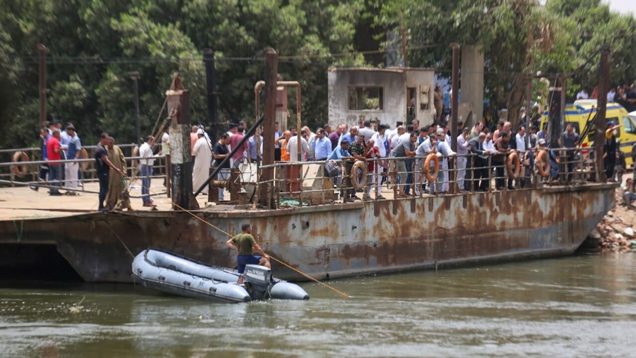 Relatives wait on the bank of a canal of the Nile River as rescuers search the waterway for casualties after a minibus sank near Abu Ghalib village in Egypt's Giza governorate