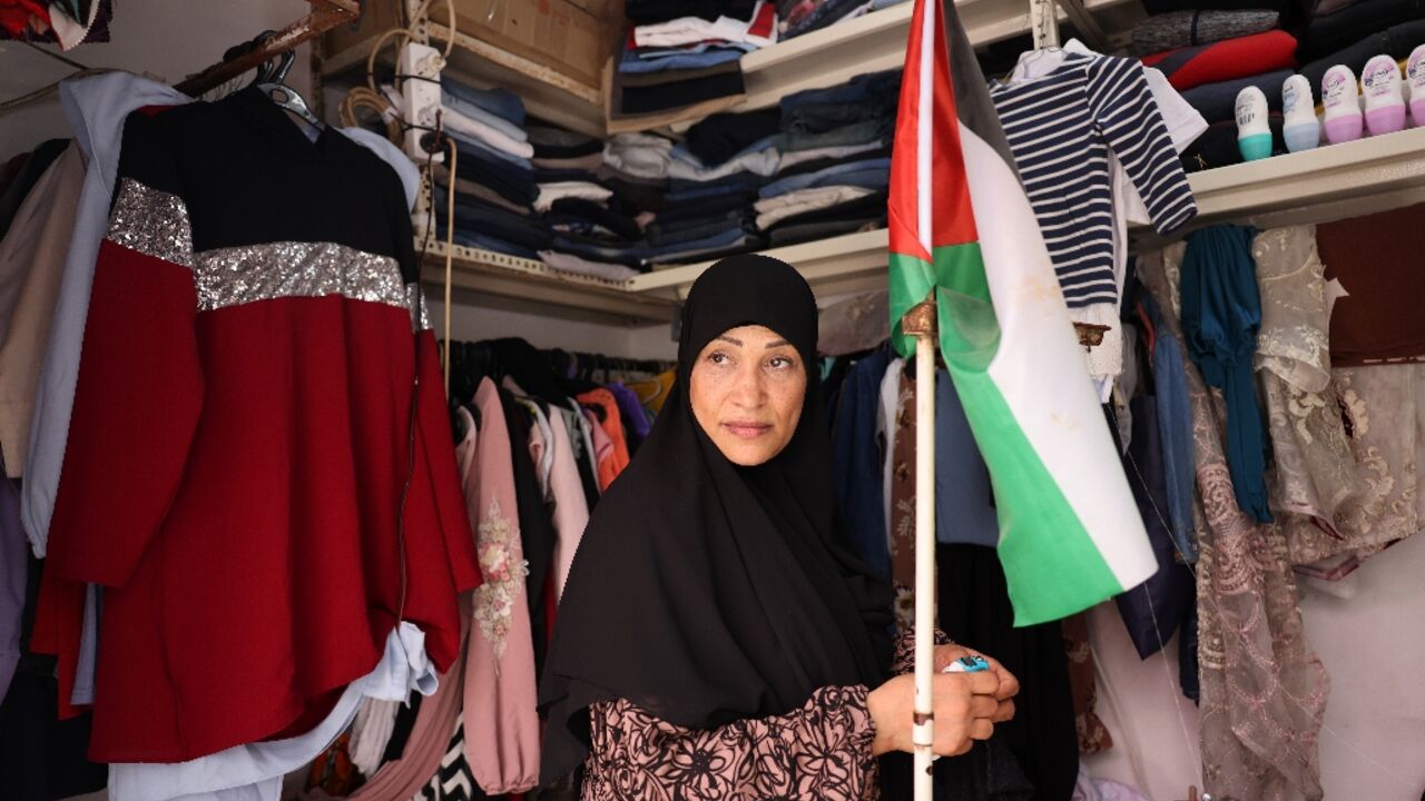 A shop owner carries a Palestinian flag in her store in the Shatila refugee camp in Beirut